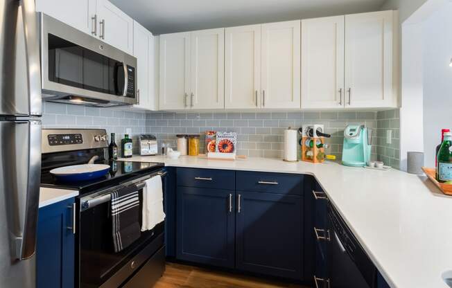 a kitchen with navy cabinets and white countertops and a stainless steel refrigerator