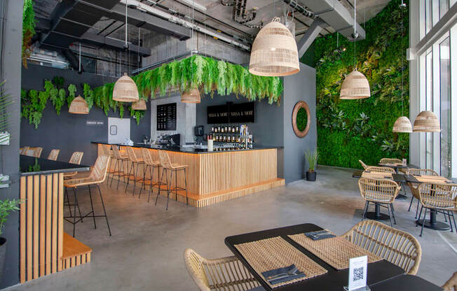 a restaurant with plants on the wall and a bar with tables and chairs