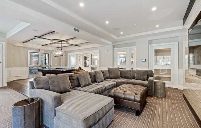 A large grey sectional sofa with a chaise lounge and ottoman in a spacious living room.