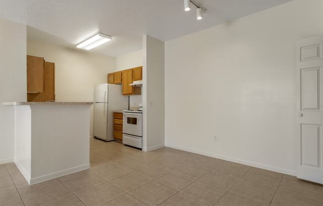 an empty kitchen with a white refrigerator and a sink
