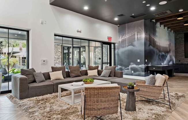 A modern living room with a grey sofa, a white coffee table, and a woven chair. at The Laurel Apartments, Arizona, 85286
