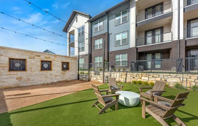 A sunny day at a modern apartment complex with a stone wall and a lawn.
