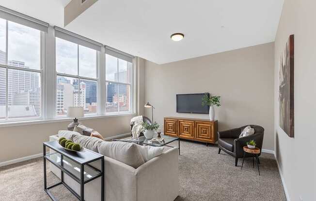 A living room with a grey couch, a black coffee table, a wooden cabinet, and a television.