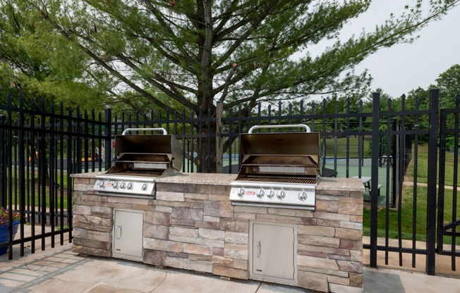 an outdoor kitchen with a grill and a tree in the background at Misty Ridge Apartments, Woodbridge