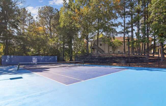 Pristine blue tennis court surrounded by trees at Oakley Run apartments in Smyrna, GA