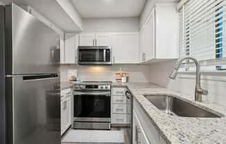 large kitchen with white cabinets, granite countertops and stainless steel appliances