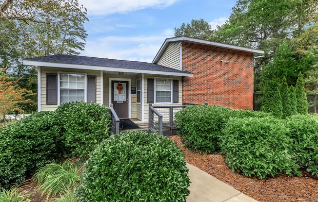 a house with bushes in front of a brick building