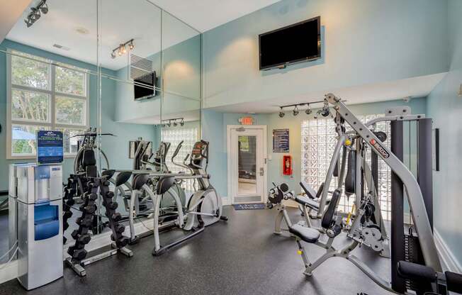 A gym with a row of exercise bikes and a television mounted on the wall.
