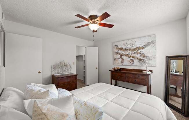 A bedroom with a large bed and a ceiling fan.