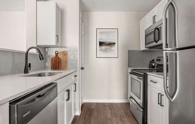 A modern kitchen with stainless steel appliances and white cabinets.