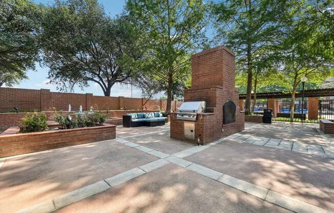 a brick fireplace in the middle of a courtyard with trees