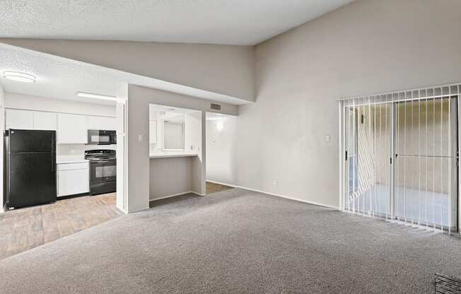 a spacious living room with a kitchen in the background