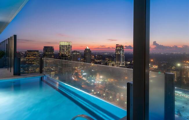 The end of the pool extends out on a ledge with a glass wall, so that the pool appears to drop off the edge of the building. Looking northeast, the viewer can see the Uptown Galleria skyline.
