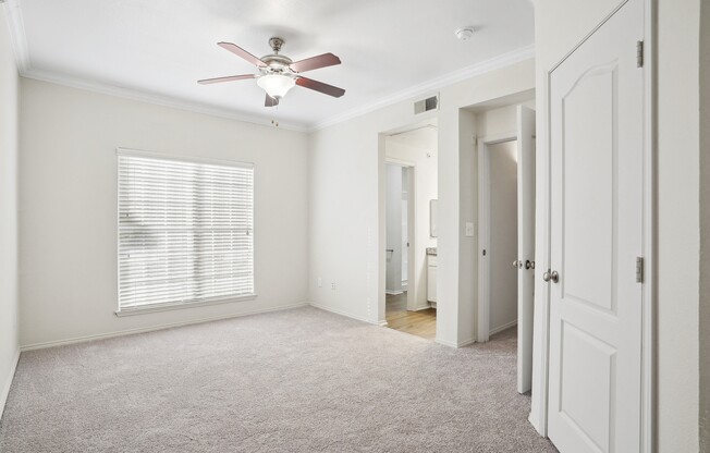an empty bedroom with a ceiling fan and a door to a bathroom at La Ventura Apartments, Texas