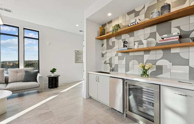 a kitchen with white cabinets and a large window at Link Apartments® Calyx, Chapel Hill, NC 27517