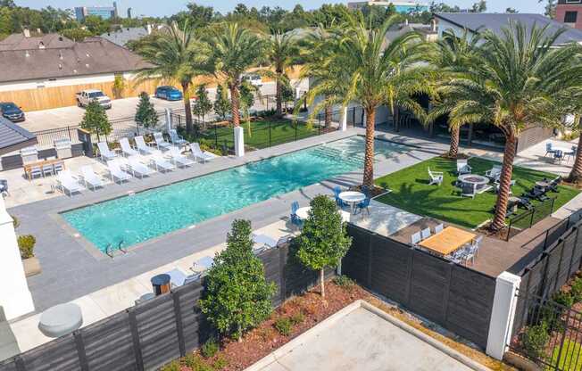 A pool surrounded by palm trees and lounge chairs.