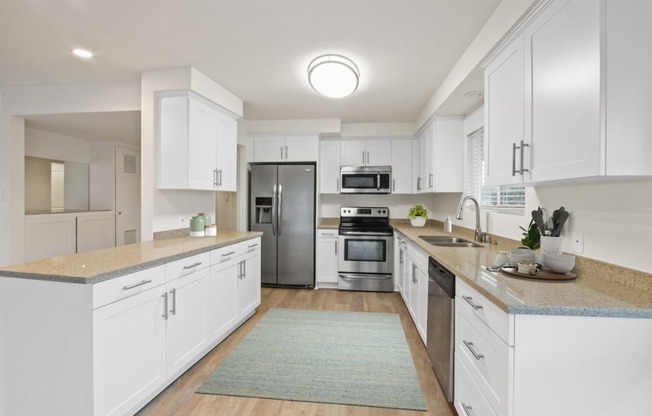a kitchen with white cabinets and a blue rug