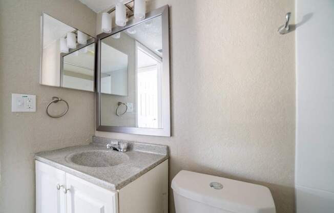 A bathroom with a sink, mirror, and toilet.