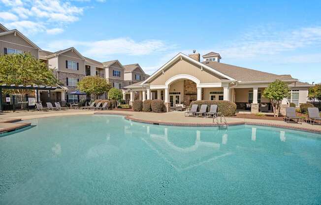 A large swimming pool in front of a building with a covered patio area.