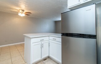A kitchen with a white cabinet and a stainless steel refrigerator.