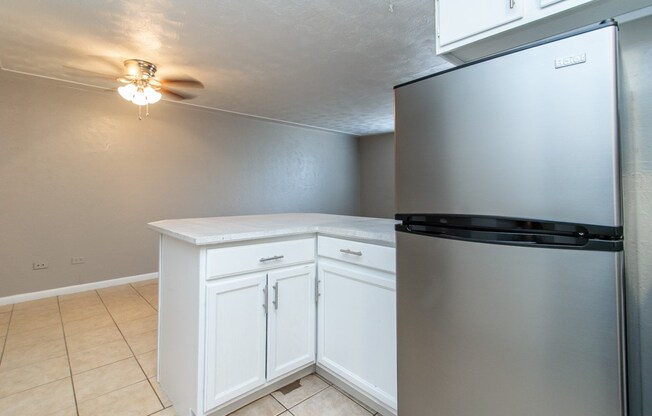 A kitchen with a white cabinet and a stainless steel refrigerator.