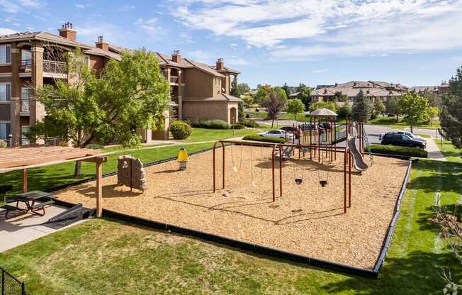 a playground in the middle of a park with houses in the background