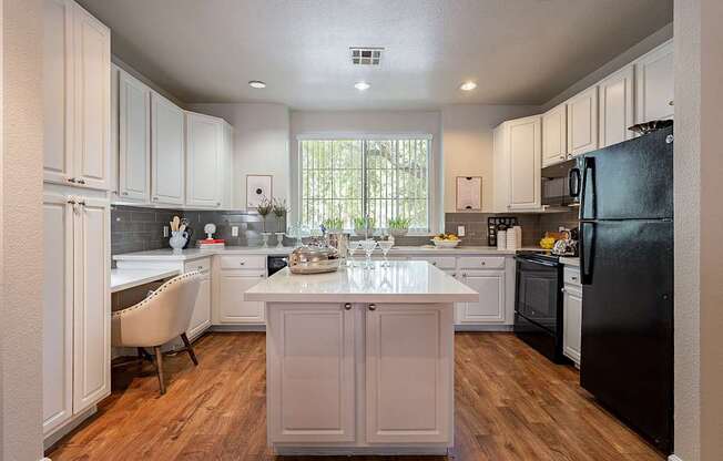 A kitchen with a black refrigerator and white cabinets.at Palazzo Townhomes, Arizona