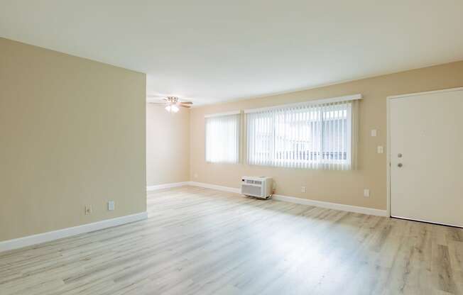 an empty living room with wood floors and a window