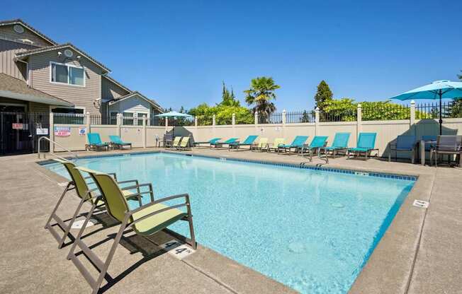A pool with blue lounge chairs and green chairs at The Madison apartments in Olympia, WA
