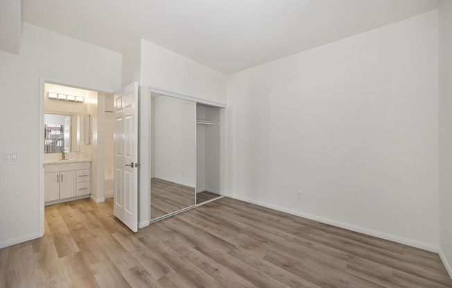 the living room of an apartment with white walls and wood flooring
