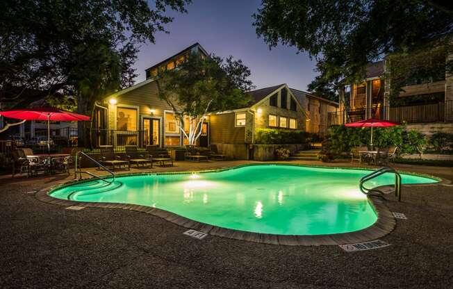 a pool at night with a house in the background