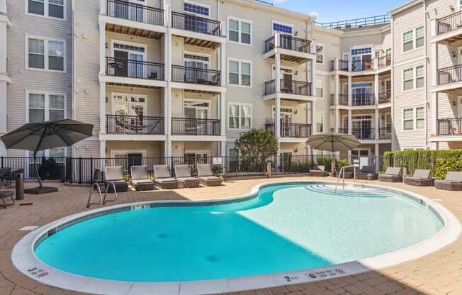 A large swimming pool in front of apartment buildings.