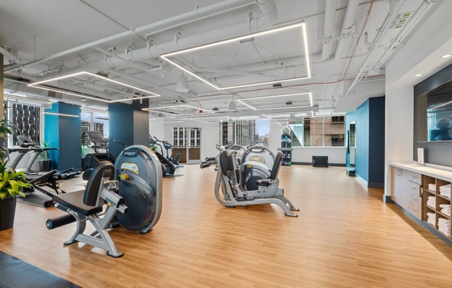 a gym with cardio machines and weights on a wooden floor