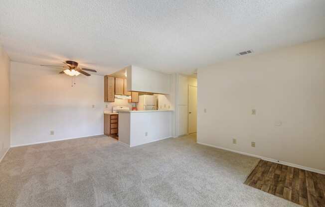 Vacant apartment Entrance and Living Room with views of the kitchen area.  Ceiling fan near the kitchen area 