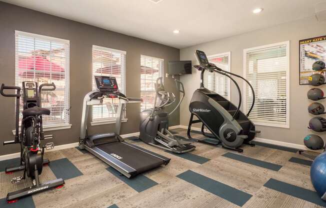A home gym with a treadmill, elliptical trainer, and stationary bike at West Park Apartments, Albuquerque, New Mexico
