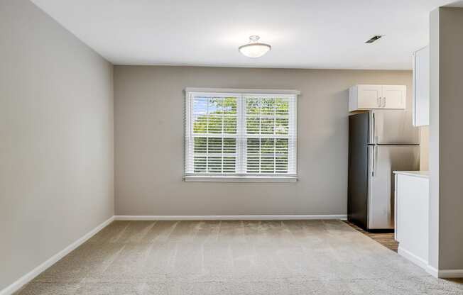 an empty kitchen with a window and a refrigerator