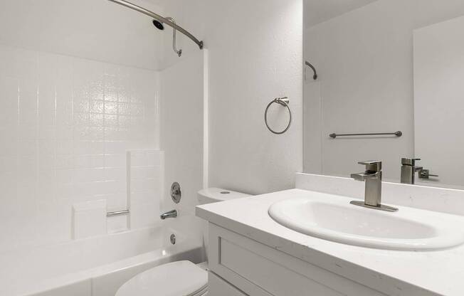 A white bathroom with a toilet, sink, and shower.