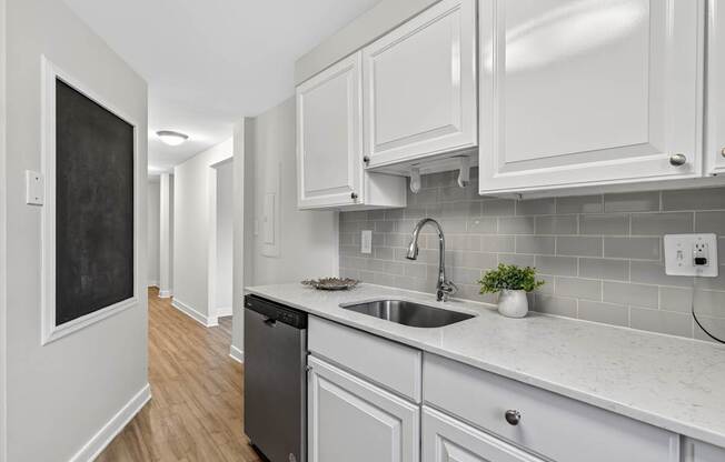 A kitchen with white cabinets and a blackboard on the wall.