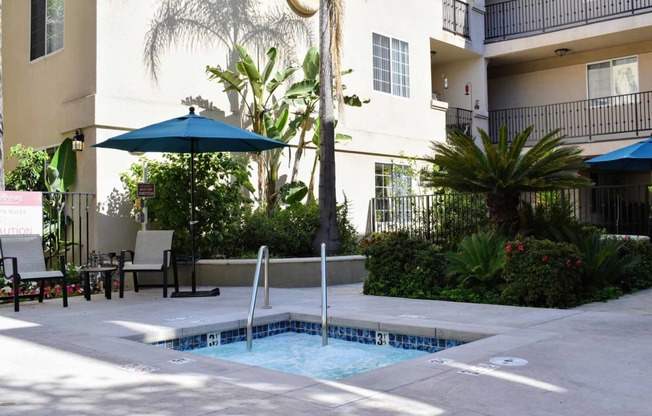 View of spa with seating and umbrella and tropical landscaping