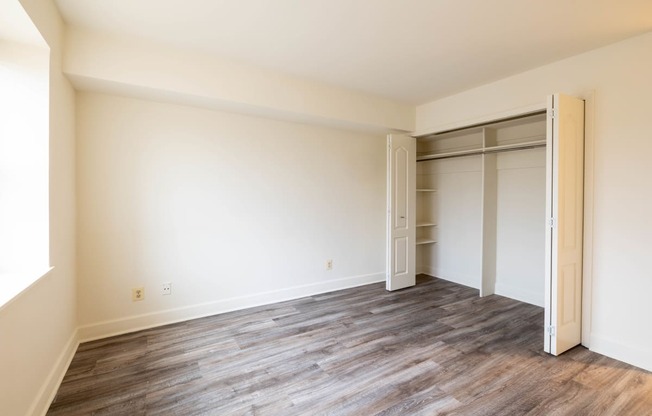 a bedroom with hardwood flooring and white walls  at Charlesgate Apartments, Maryland, 21204