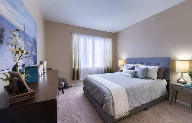 A bedroom with a large bed and a painting on the wall.