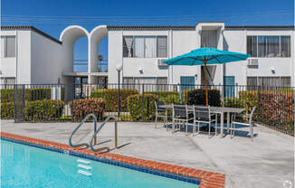 our apartments have a swimming pool and a patio with a table and umbrellaat The Arches Apartments, LLC, El Cajon California
