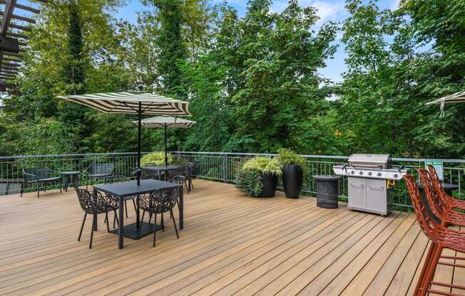 A wooden deck with a table and chairs and a grill.
