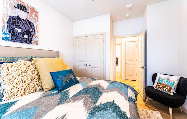 Bedroom with a bed and a chair and a door to a bathroom at The Parker Austin, Pflugerville, Texas