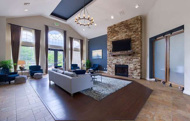 A modern living room with a stone fireplace and a large grey sofa.
