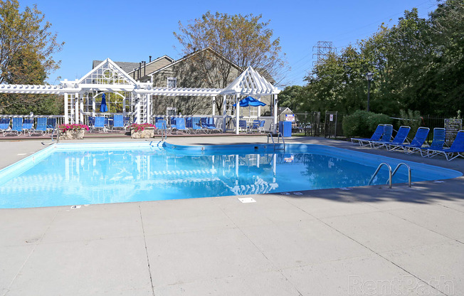 a swimming pool with chairs around it and a house in the background