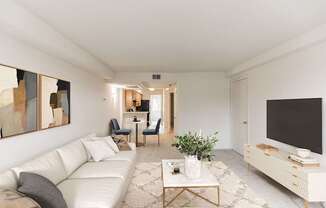 A living room with a white couch, a coffee table, and a television.