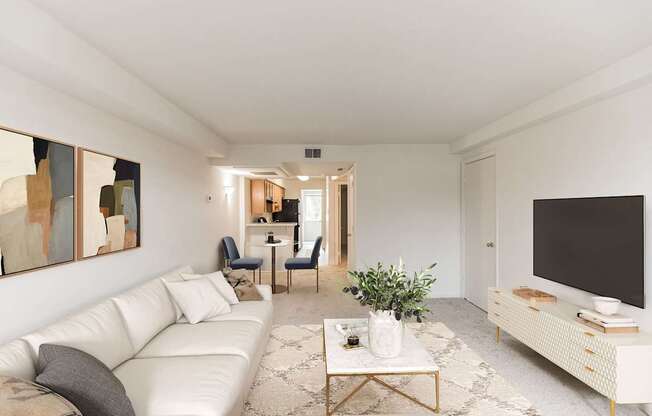 A living room with a white couch, a coffee table, and a television.
