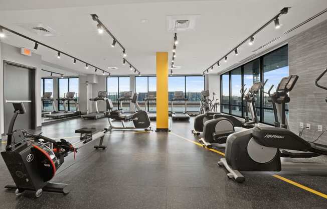 a gym with cardio equipment and floor to ceiling windows with a view of the city