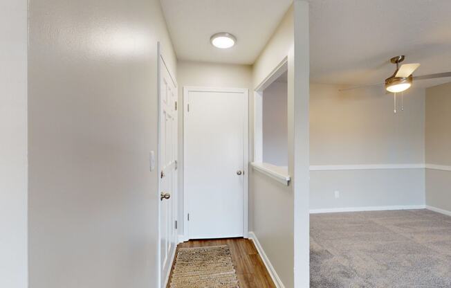 the living room and hallway of a manufactured home with white walls and wood flooring